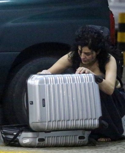 Letícia organiza seus pertences no chão do estacionamento. (Foto: Reprodução)