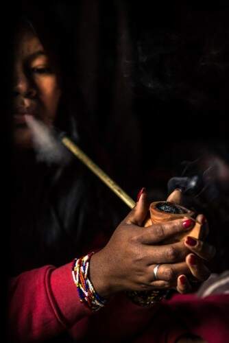 Cotidiano da polução Guarani em evidência: indígena fumando um cachimbo. (Foto: Vherá Poty e Danilo hristidis/reprodução)