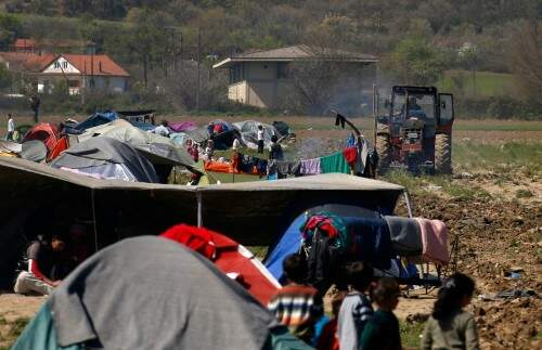 Lazaros Oulis é visto em trator ao lado de tendas de refugiados em sua fazendo em Idomeni, na Grécia (Foto: AP Photo/Darko Vojinovic)