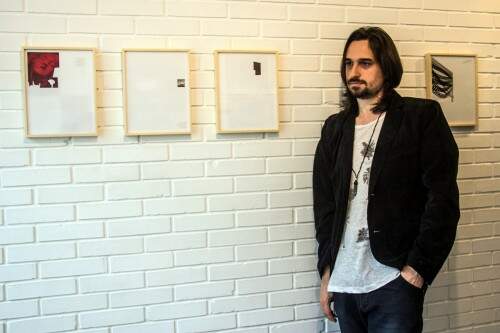 Daniel Escobar ao lado da série “Coleção Particular”, composta por páginas de revistas com imagens de obras de artistas renomados. (Foto: Jackson Ciceri/O Sul)